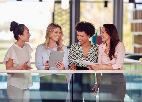 Multi-cultural,Female,Business,Team,With,Digital,Tablet,Meeting,Inside,Modern